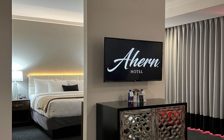A hotel room with a king-sized bed, flat-screen TV, and cabinet.