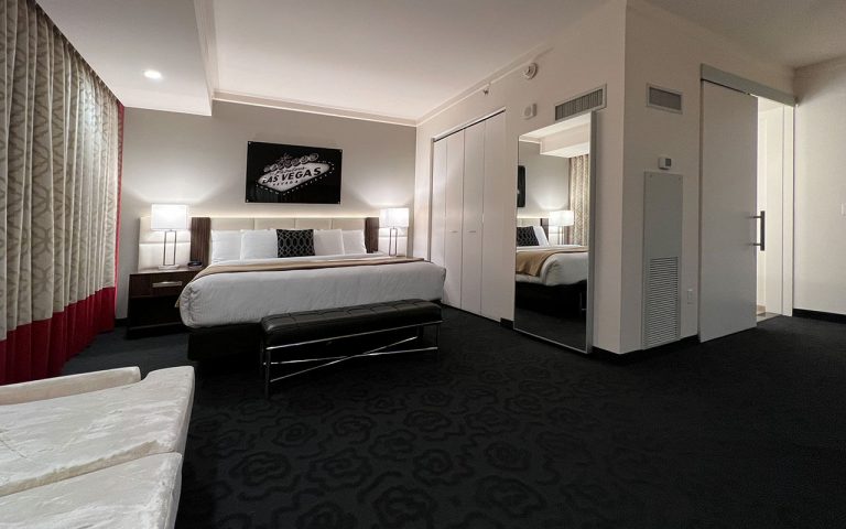 A wide view of a hotel room with a bed, sofa, and nightstand.