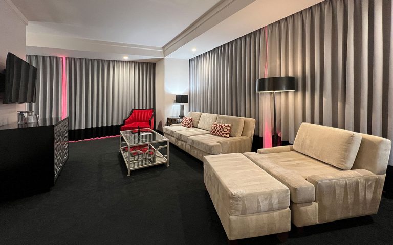 A wide view of a luxurious living room with a sofa, chair, coffee table, and TV.