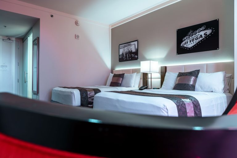 A hotel room with two beds, a lamp, and artwork on the walls.